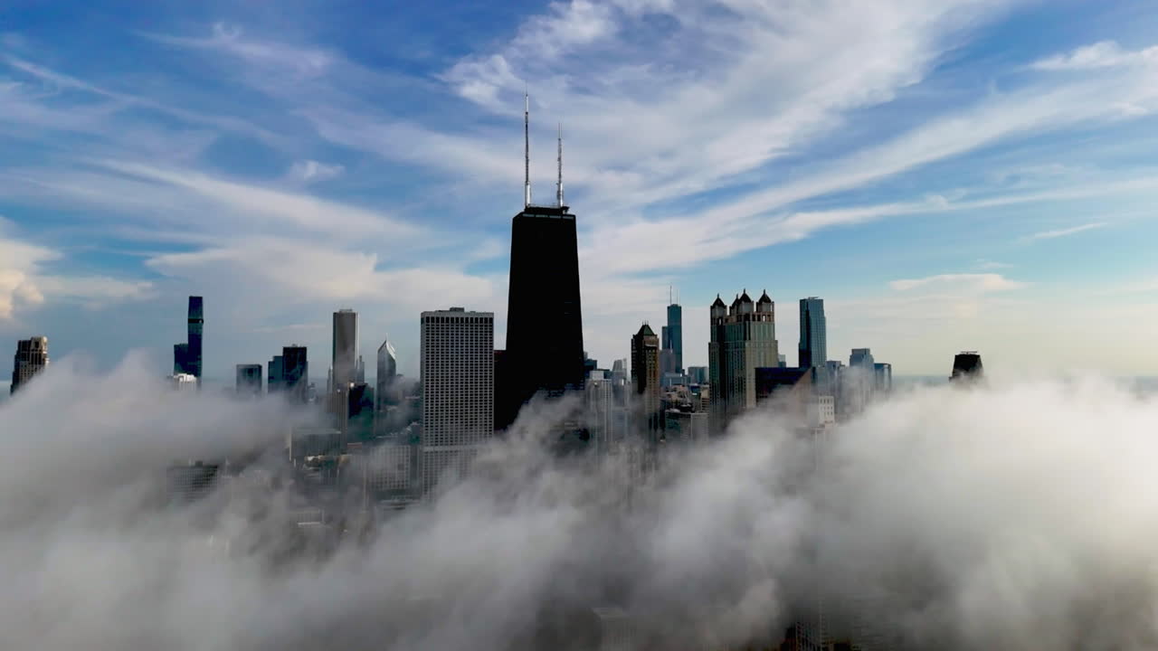 Aerial pull back shot of low hanging clouds in front of the Chicago skyline