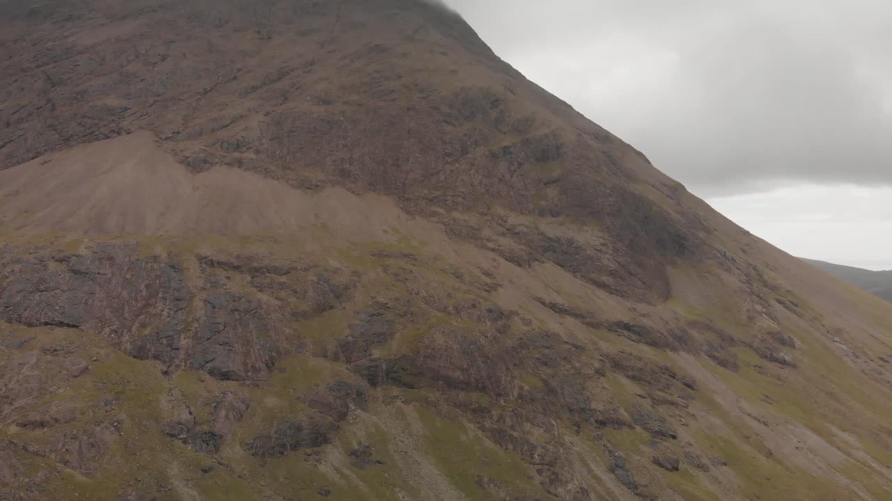 drone avanzato girato nell'isola di skye highlands scozia, vista ravvicinata di un'alta montagna con erba verde e rocce in una giornata nuvolosa