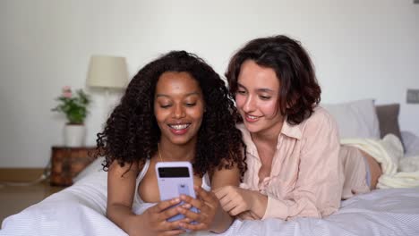 sonrientes novias diversas tomando selfies con teléfonos inteligentes a la luz del día