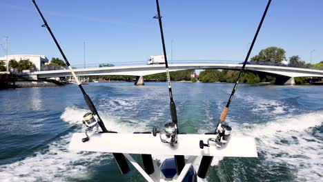 boat moving under bridge with fishing rods