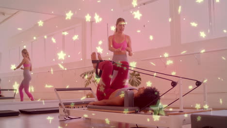 stars animation over women exercising on pilates reformers in fitness studio