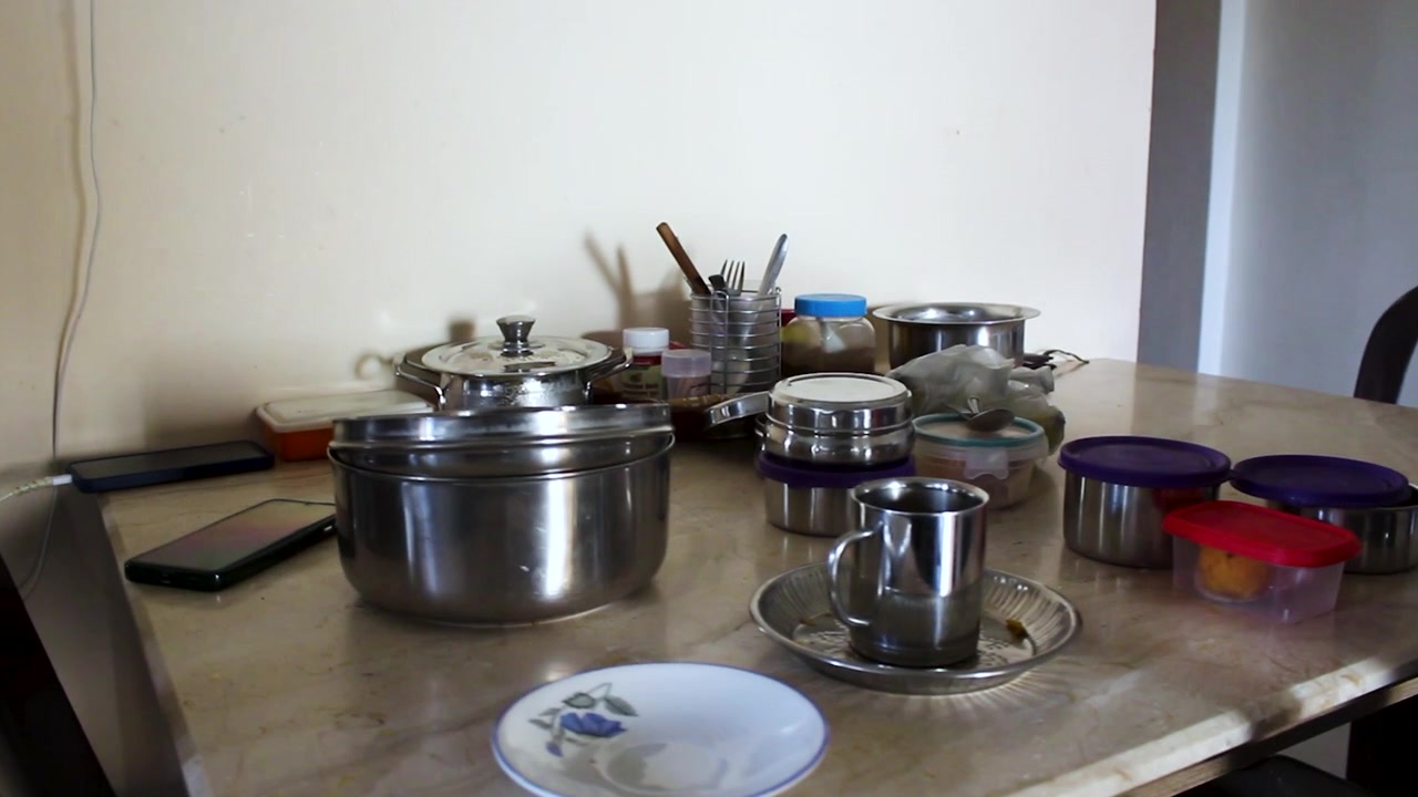 Real-life Indian household dining setup with stainless steel containers, utensils, and prepared food on table. Ideal for family meal, home lifestyle, and domestic living content.