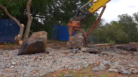 a large excavator lifting a heavy boulder on a construction site