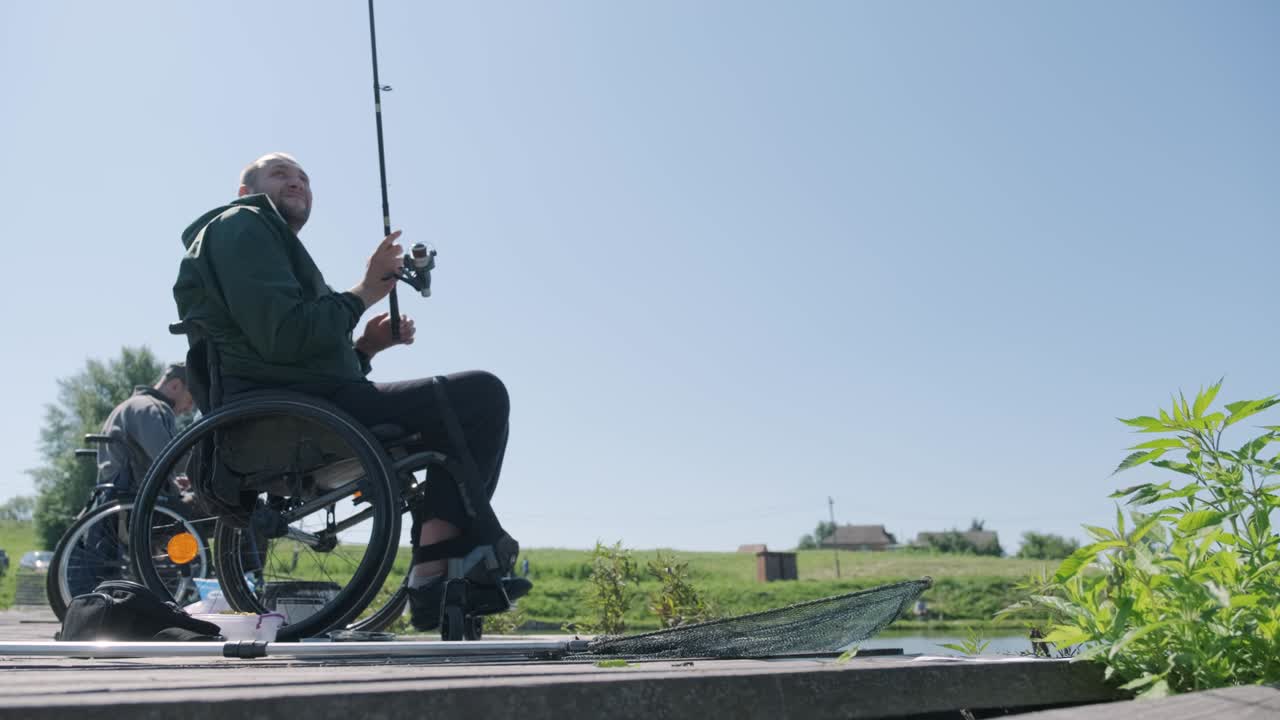 Man with disabilities fishing at a lake. Wheelchair. Summertime. Disabled person fishing