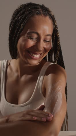 studio skincare beauty shot of woman dispensing moisturiser and pretending to rub it into camera lens