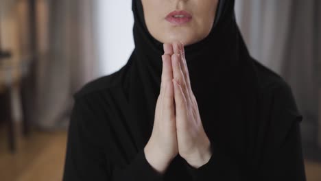 close-up of female hands folded together. unrecognizable young muslim woman praying at home. religion, lifestyle, culture.