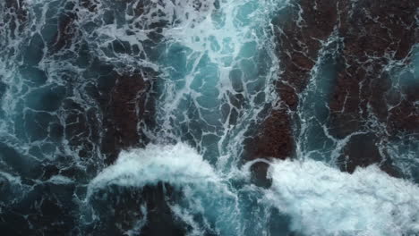 bird's eye view of powerful waves crashing on rocky coastline, tracking shot