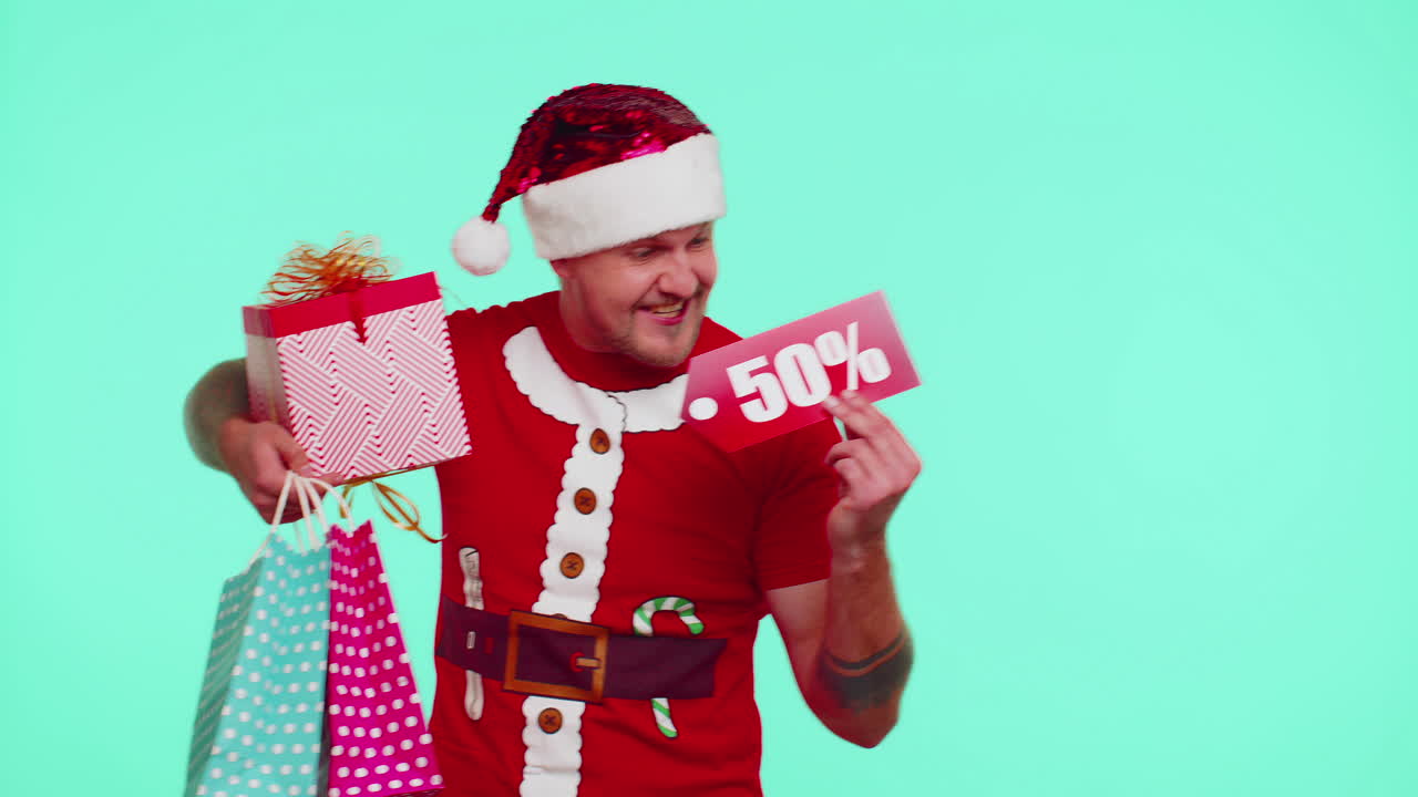 hombre con camiseta roja de navidad mostrando caja de regalos y inscripciones de descuento del 50 por ciento nota de texto de banner