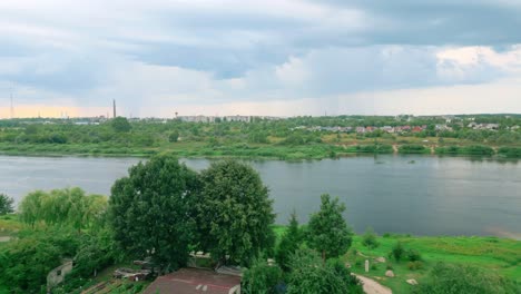 drone footage capturing the crossing over the daugava river with a view of a boat in the water and daugavpils city in latvia in the background under a cloudy sky