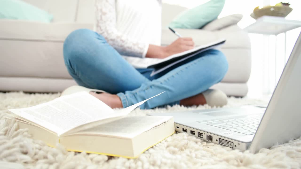 바닥에 앉아 노트패드에 글을 쓰는 여자