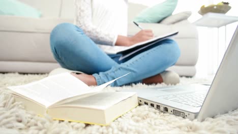 mujer sentada en el suelo escribiendo en el bloc de notas