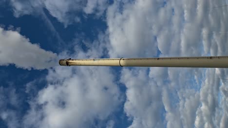 smoking chimney viewed from below against a cloudy sky, vertical