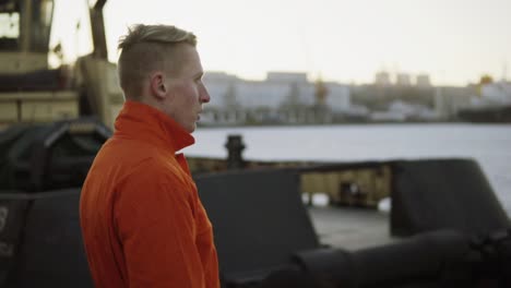 harbor worker in orange uniform smoking a cigarette during his break and relaxing. slow motion