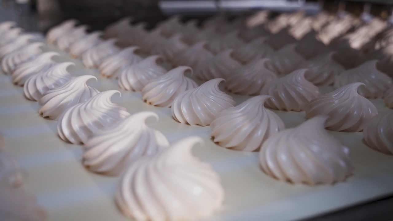 Sweet white swirl marshmallows on a conveyor belt. Production of confectionery products at the factory. Drying process