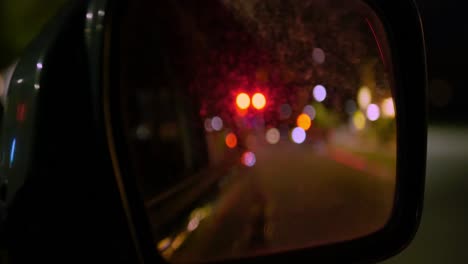 Driving-in-passenger-seat-of-green-car-at-night-bokeh-lights-in-rear-side-view-mirror-objects-closer-than-they-appear