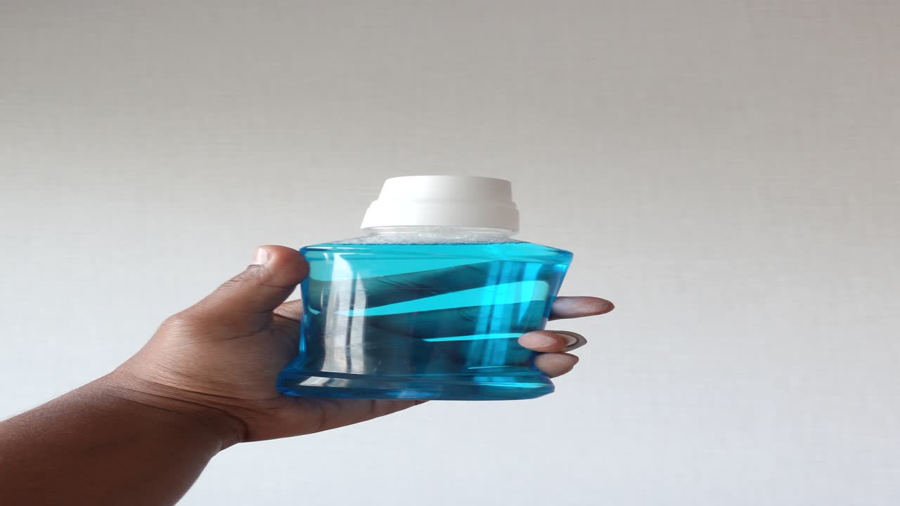 mano con una botella de enjuague bucal