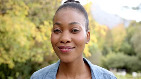 portrait of happy african american woman looking at camera and smiling in garden, in slow motion