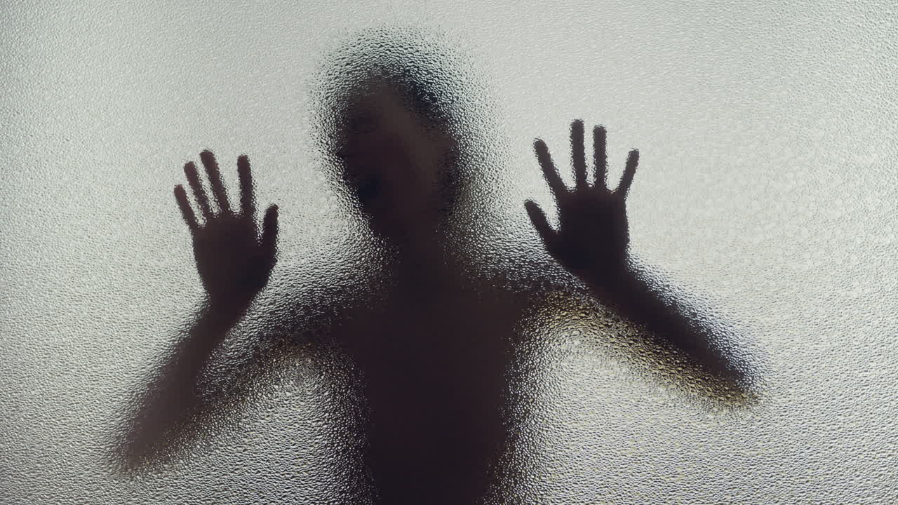 A female silhouette behind the frosted glass moves slowly and screems