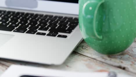 coffee mug, laptop, mobile phone on wooden plank