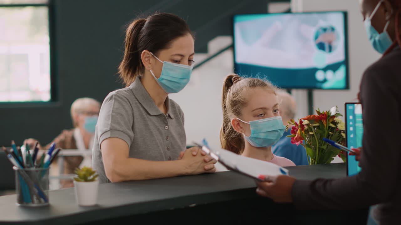 Two patients with face mask talking to facility receptionist