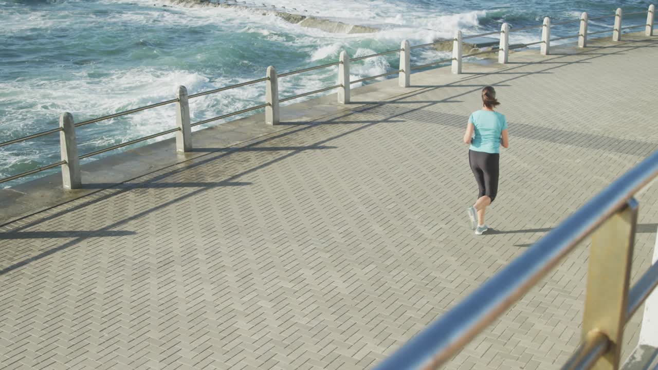 mujer mayor corriendo en un paseo marítimo