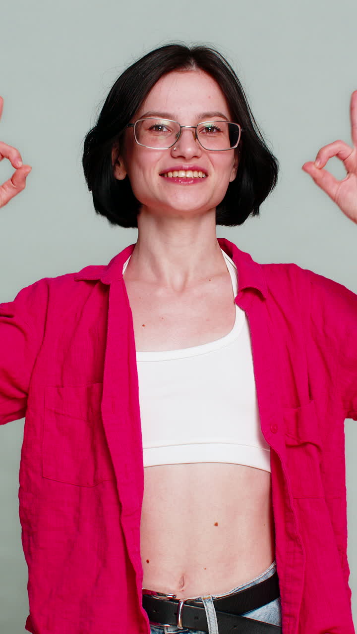 Giovane donna sorridente che annuisce mostrando un gesto di approvazione con le dita, reazione positiva di consenso