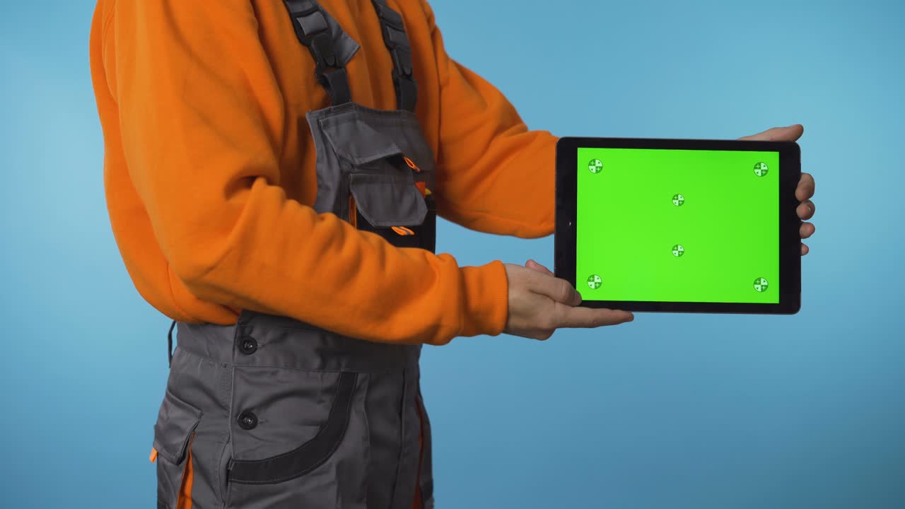 trabajador de la construcción sosteniendo una tableta de pantalla verde en el lado para la promoción del producto