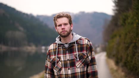 a panning glance behind the camera, followed by a hearty laugh, show a young blond man on a path next to a river