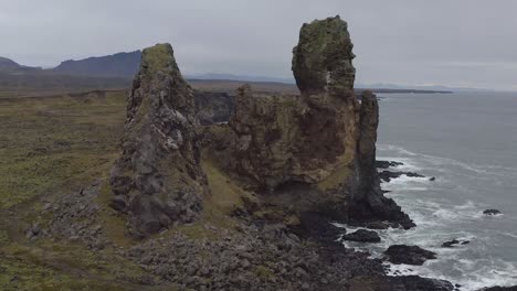 Flying-around-Londrangar,-a-pair-of-rock-pillars-on-the-coast-of-Snaefellsnes-in-Iceland