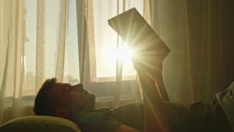 man reading in bed at sunrise