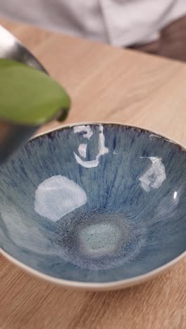 chef pouring green soup into a bowl