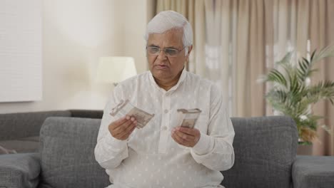 sad indian old man counting money