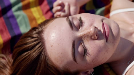 close-up of a woman with freckles relaxing on a striped blanket