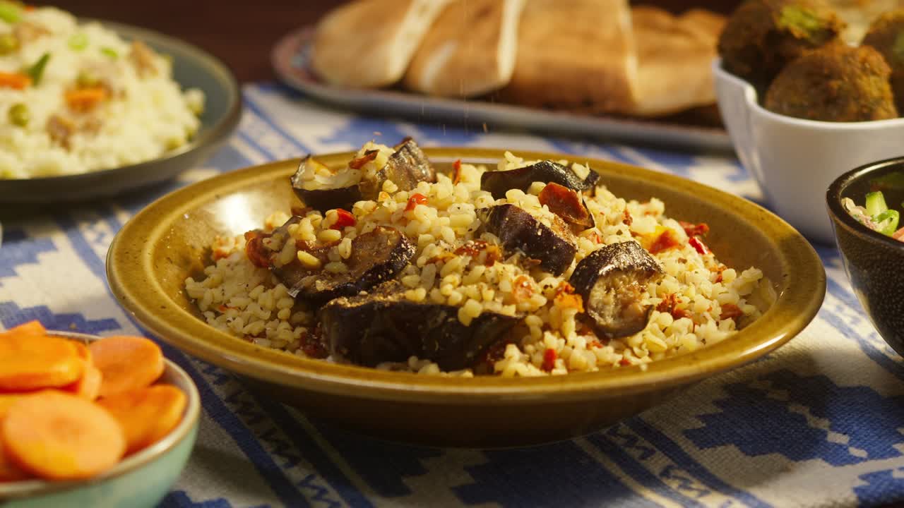 salpicando pimienta en bulgur con berenjena de primer plano, cuscús con carne en el fondo. cultura tradicional de oriente medio. delicioso arroz con carne. cocina árabe. concepto de comida casera