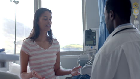 Diverse-female-patient-and-male-doctor-talking-standing-in-hospital-ward,-slow-motion