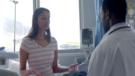 paciente femenina diversa y médico masculino hablando de pie en la sala del hospital, cámara lenta