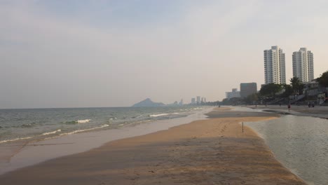 person walking on beach with city skyline
