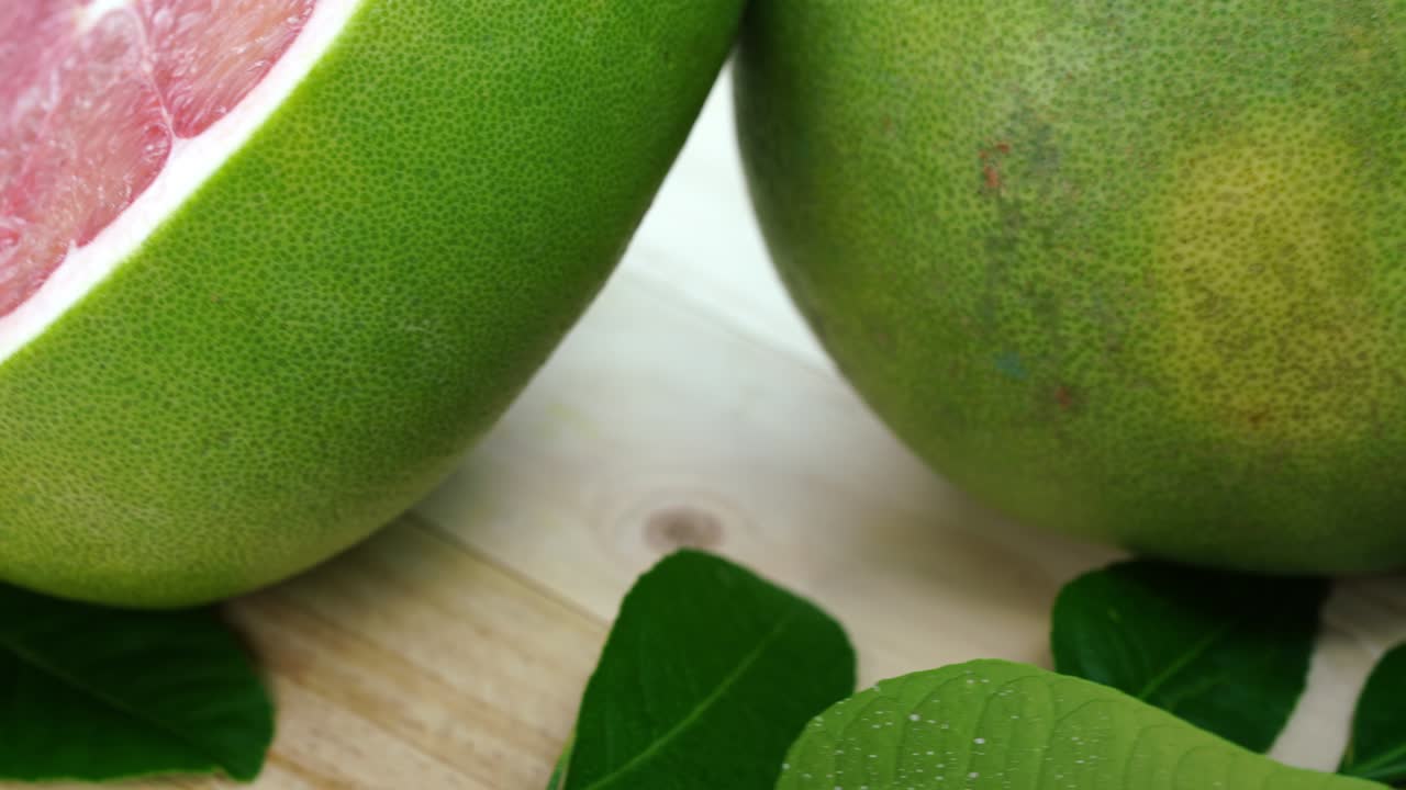 vista superior girar la fruta de pomelo roja con hojas en la mesa de madera en el jardín, la fruta del pomelo rojo con hojas con fondo de madera resolución 4k.