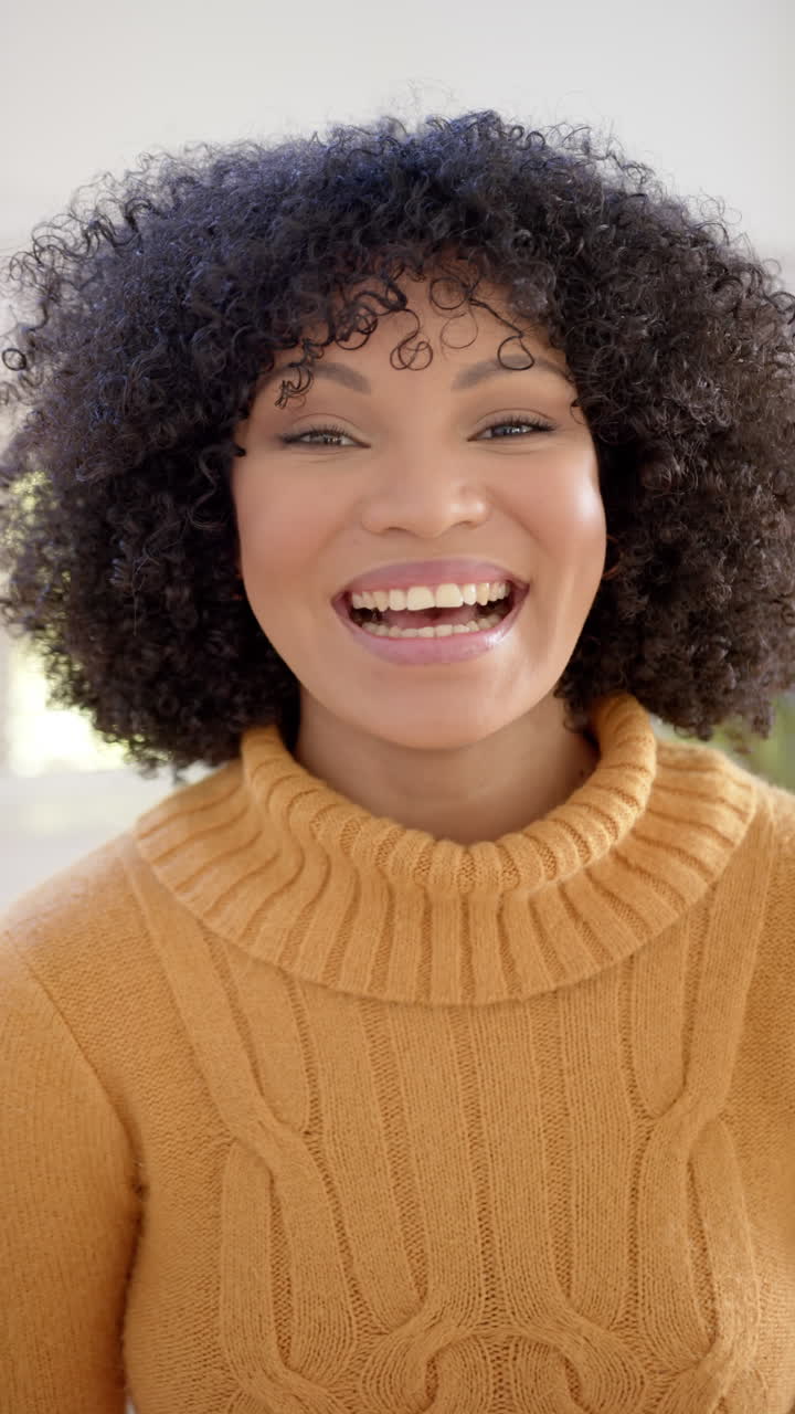 Vertical video of portrait of happy african american woman at home, slow motion