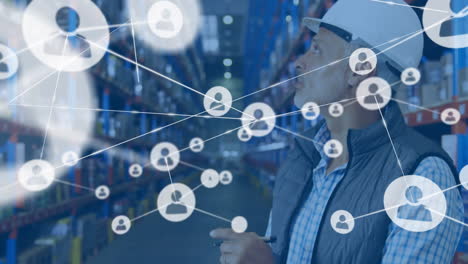 animation of network of connections with icons over man writing on clipboard in warehouse