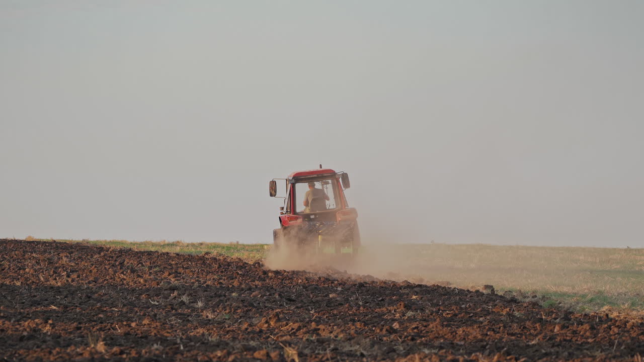 Tractor working on large field. Farmer in tractor preparing land with seedbed cultivator