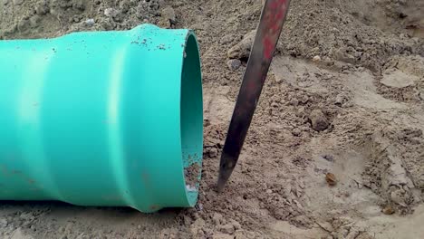 a construction worker drives a spike into the ground in preparation for assembling gravity sewer pipe on a construction site