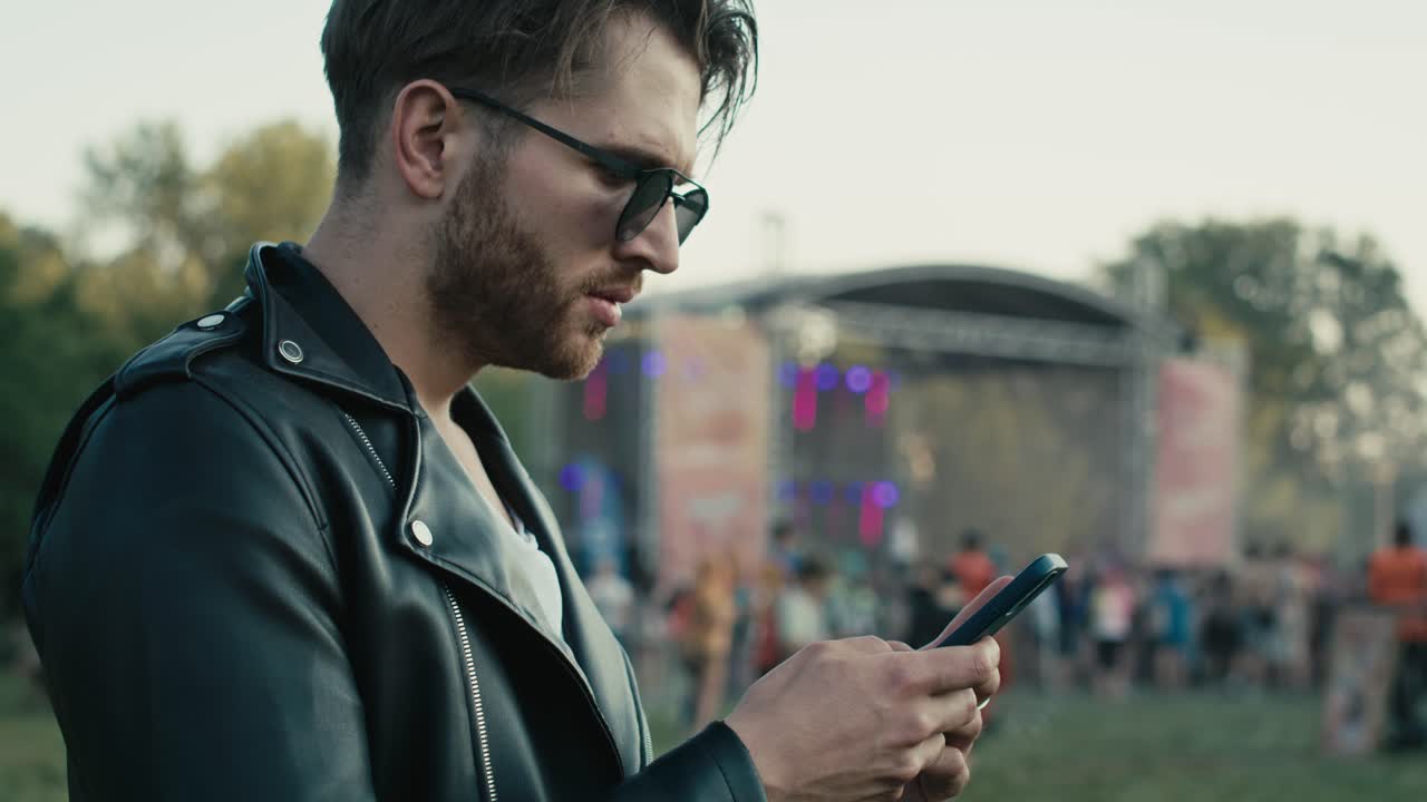 Giovane uomo caucasico a un festival musicale che usa il telefono