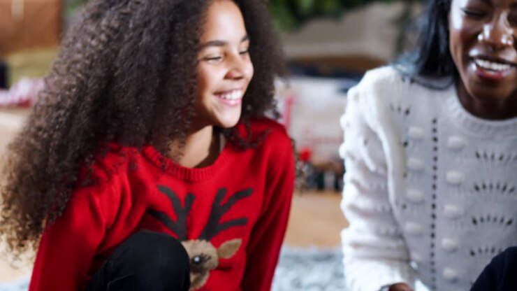 Spændte børn sidder på gulvet med mor, mens familien fejrer jul sammen