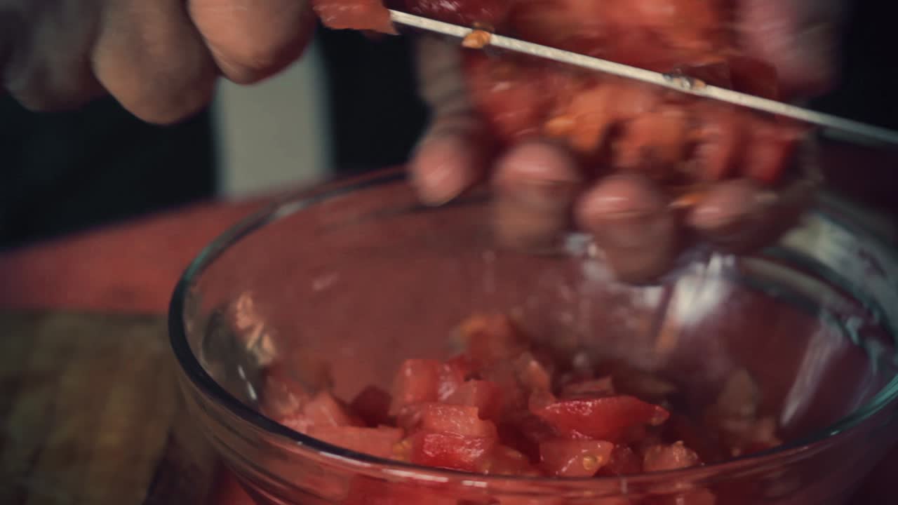 las manos cierran cortando un tomate en cuadrado para ensalada.