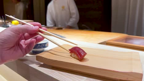 chef prepares and serves sushi with chopsticks