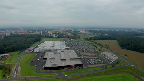 Aerial-drone-shot-of-a-czech-big-city-Ostrava-with-shopping-park,-buldings,-cars,-roads-and-apartments-and-Beskydy-mountains-during-cloudy-day