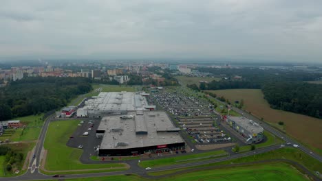 toma aérea de un avión no tripulado de una gran ciudad checa ostrava con parque comercial, edificios, coches, carreteras y apartamentos y montañas oscuras durante un día nublado