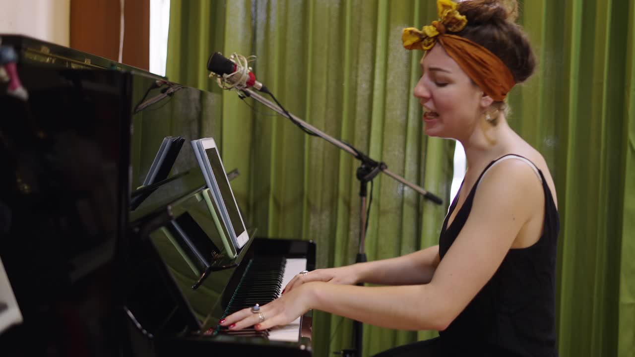 A Woman Playing Piano and Singing into a Microphone