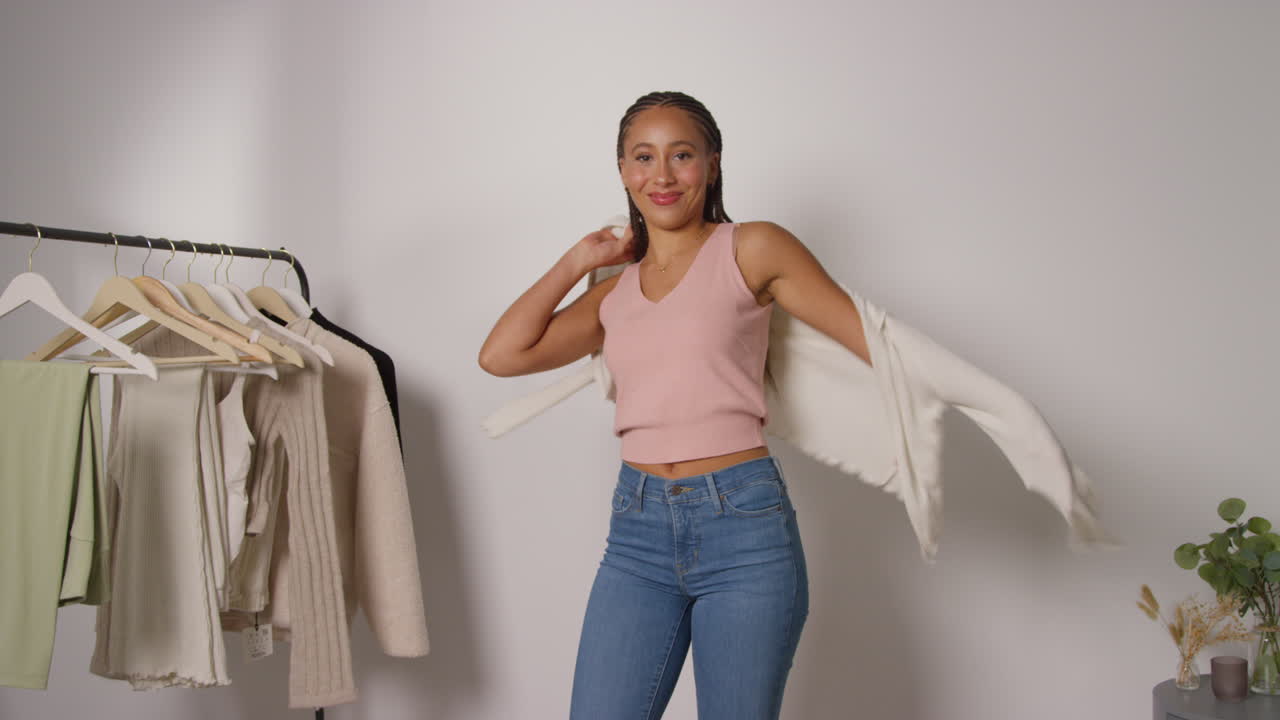 influencer femenina de redes sociales produciendo contenido generado por el usuario en el estudio probando una variedad de trajes de moda filmados en tiempo real 1